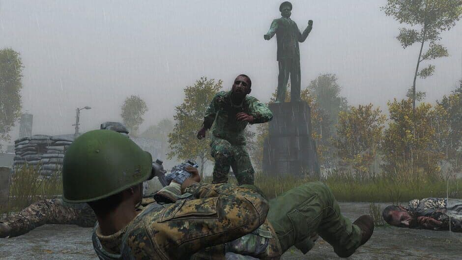A DayZ survivor fights through infected near a statue in heavy rain.