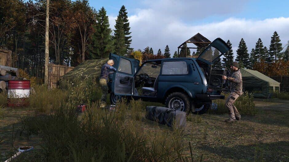 A DayZ woodland camp with a wooden fence, a barrel, a tent and a watchtower, and a duffel bag left loose on the grass