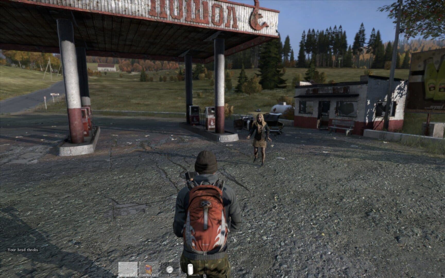 A DayZ survivor watches a stranger approach across the forecourt of an abandoned petrol station in Chernarus.