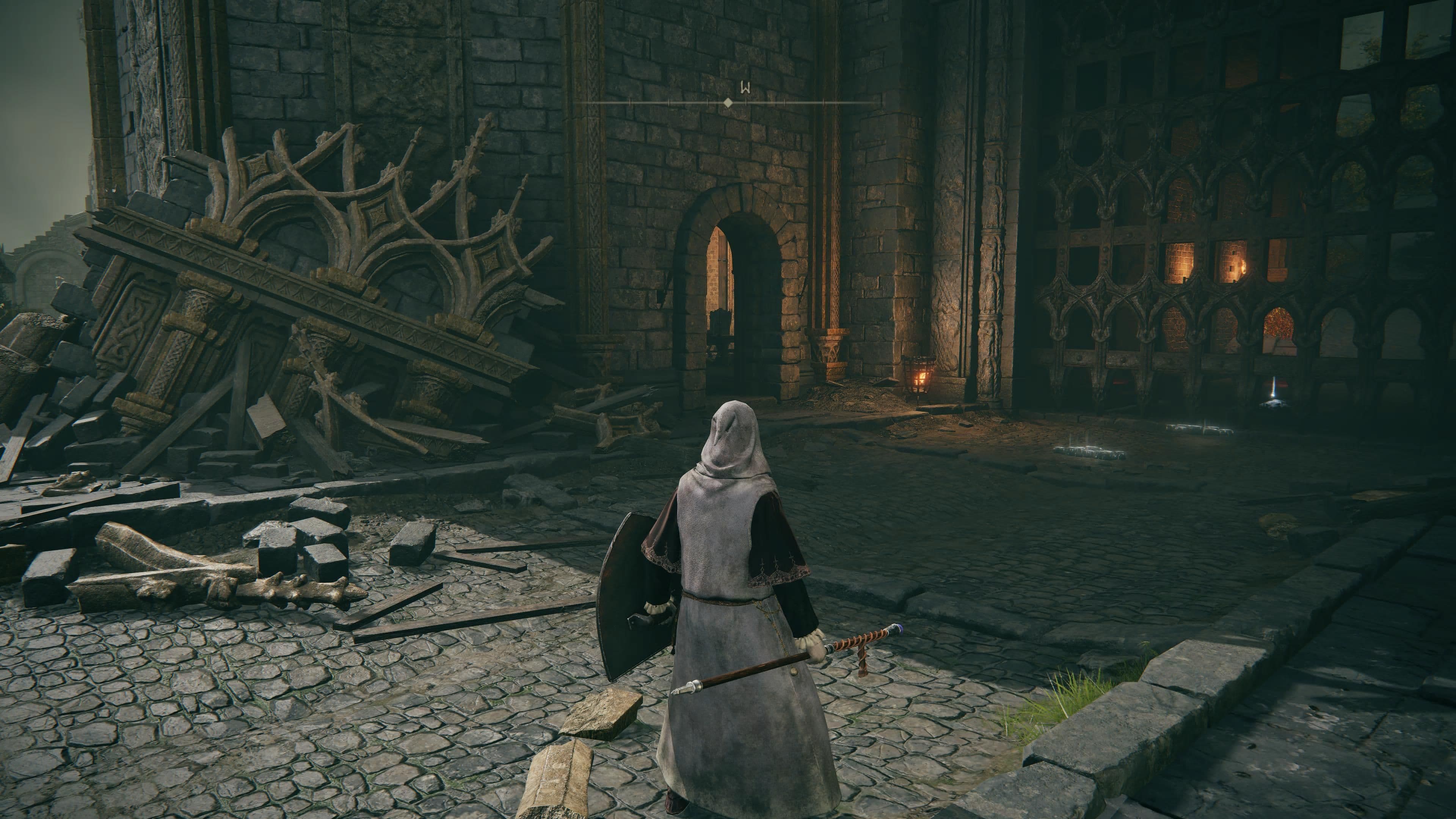 Un personaje jugador explora los muros de piedra en ruinas y las puertas dentro del Castillo de Velo Tormentoso de Elden Ring.