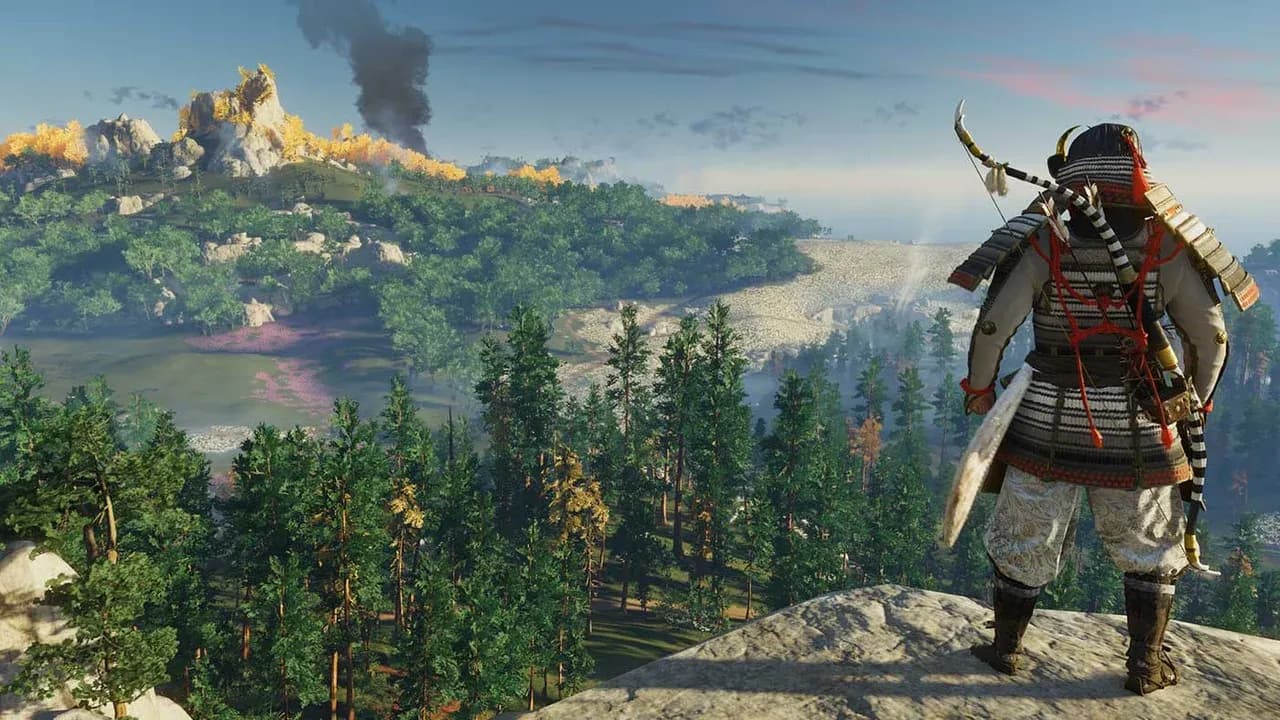 A samurai in traditional armor overlooks a lush autumn landscape with rising smoke in Ghost of Tsushima.