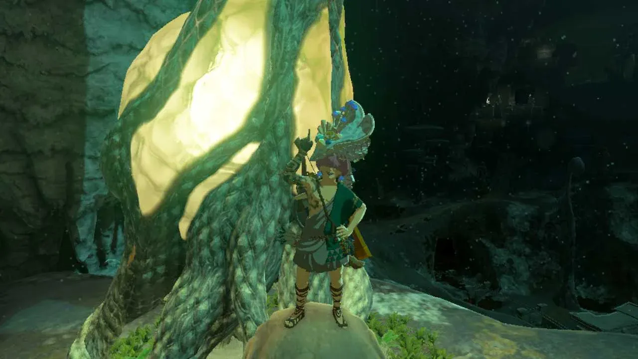 Link stands before a glowing Lightroot in the dark Depths of Zelda Tears of the Kingdom while holding Zonaite.
