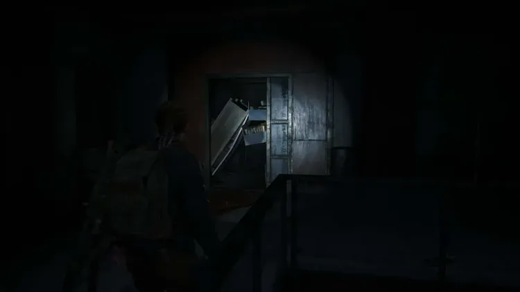 Abby explores the dark, debris-filled hospital corridors before encountering the Rat King in The Last of Us Part II.