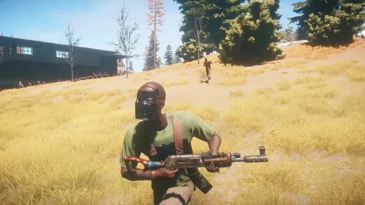 A Rust player wearing a Metal Facemask and carrying an assault rifle in open grassland