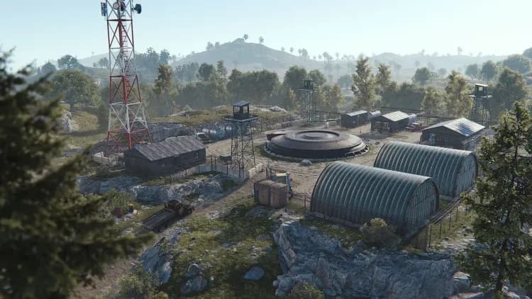 Aerial view of Rust's Nuclear Missile Silo surface compound, with the domed blast hatch, red-and-white radio tower, watchtowers and two corrugated hangars