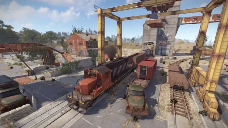 Rust Trainyard locomotive and loaded freight cars beneath the yellow unloading gantry