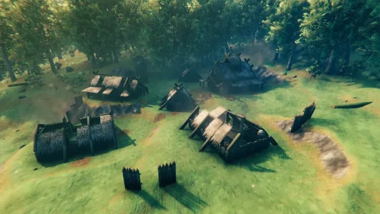 A Valheim Draugr Village in the Meadows seen from raised ground, with roofless halls and sections of sharpened-log palisade in the foreground