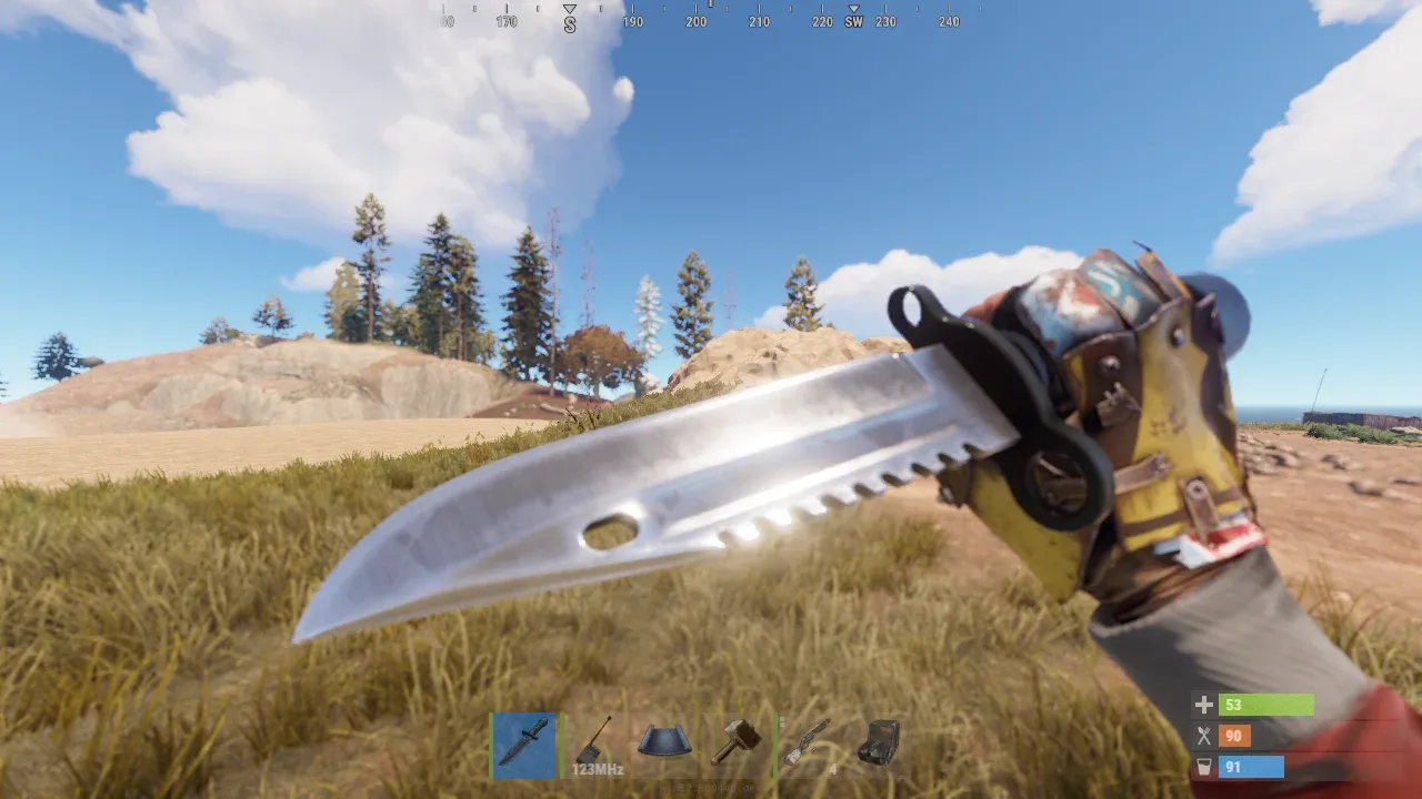 First-person view of the Combat Knife equipped in Rust, held in a gloved hand over open grassland