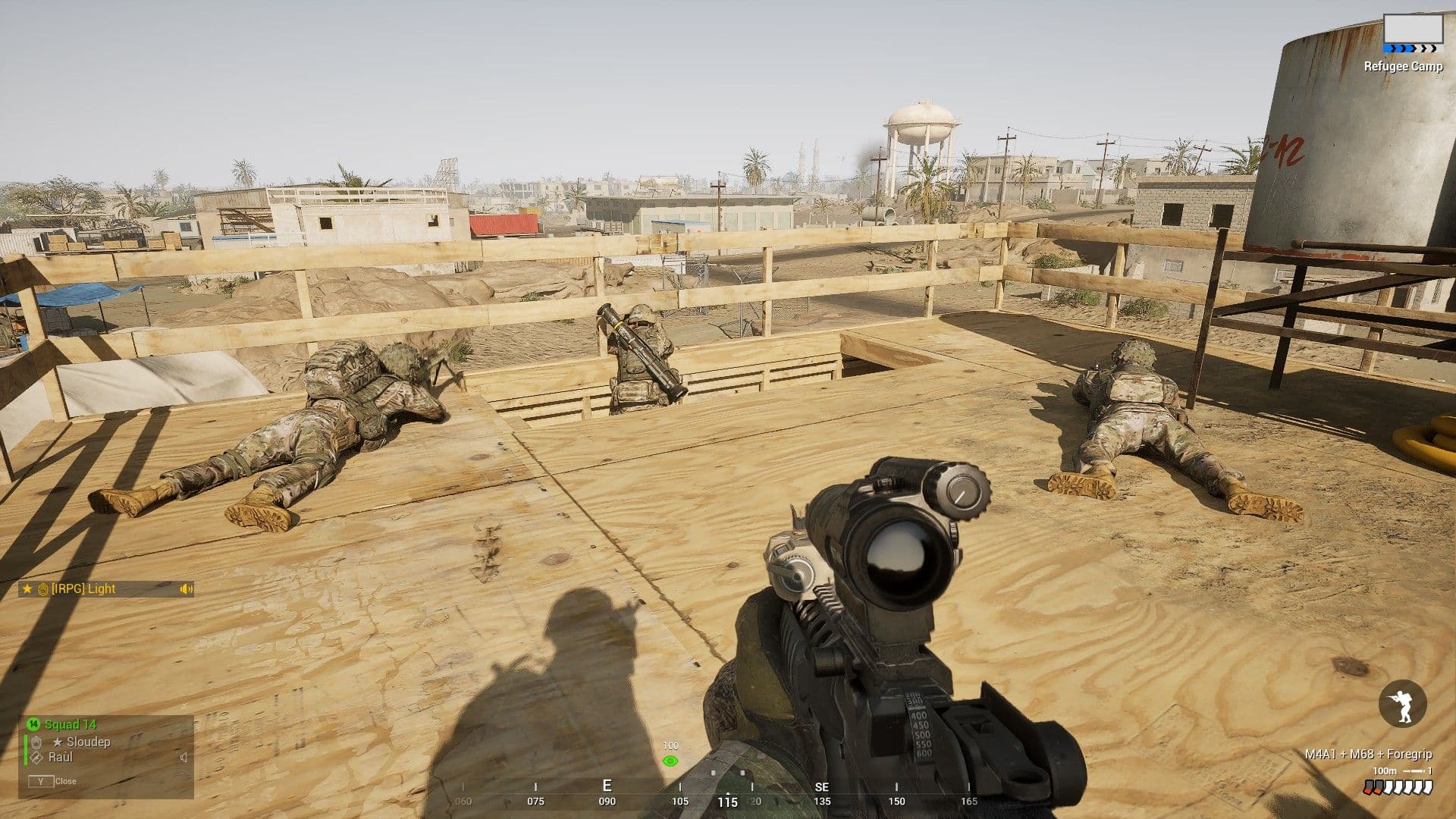 A US Army fireteam in Squad holding a plywood rooftop over a Middle Eastern shantytown — two soldiers prone and facing outward, a third crouched at the timber parapet with an anti-tank launcher.