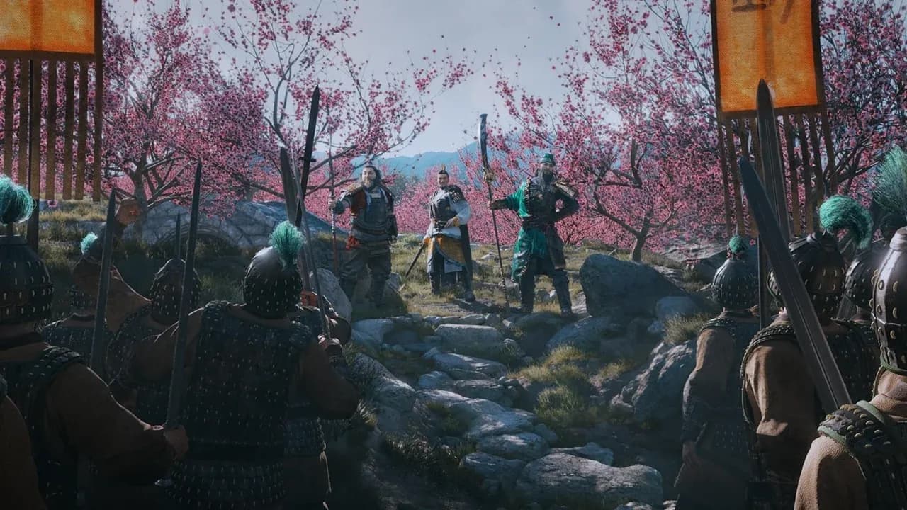Total War: Three Kingdoms commanders Guan Yu and Zhuge Liang stand before their army amidst pink blossom trees.