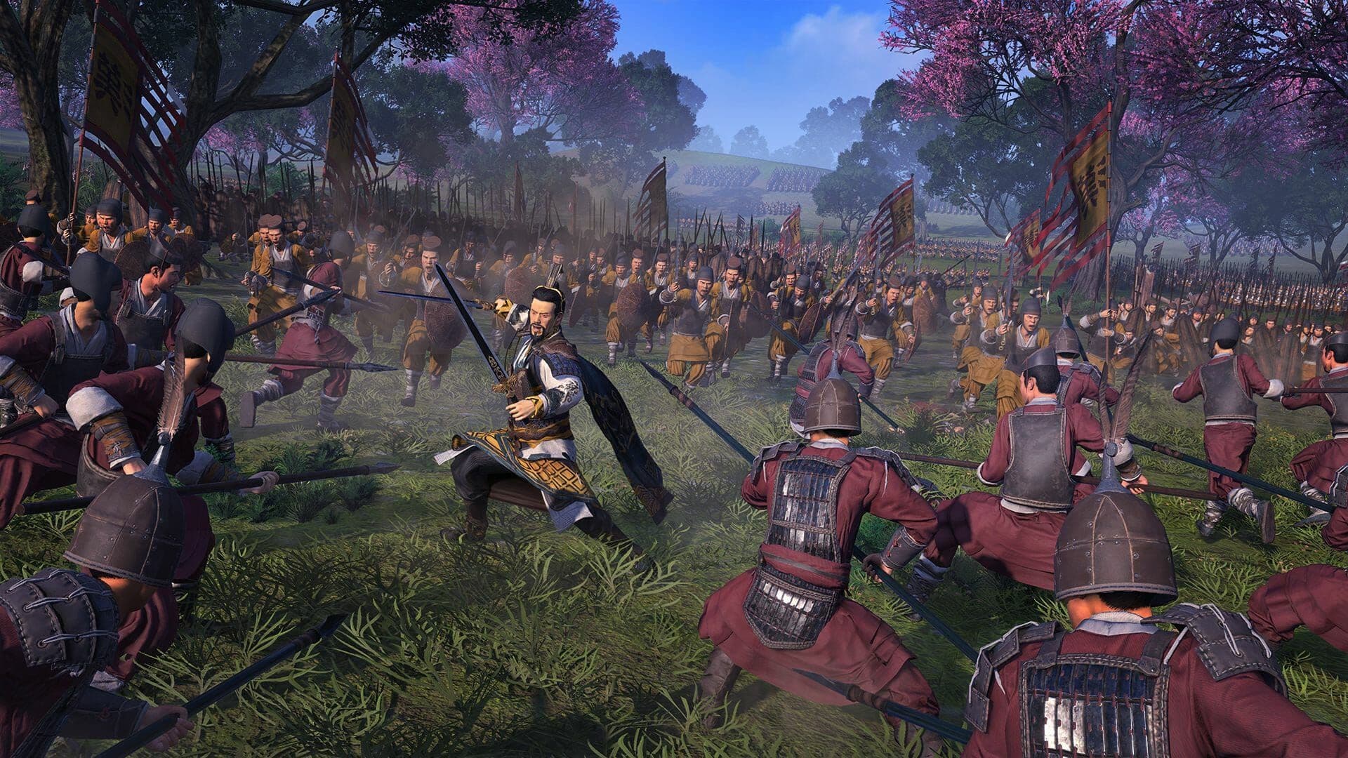 A massive battlefield in Total War: Three Kingdoms features soldiers in traditional armor fighting near flowering trees.